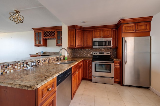 kitchen with tasteful backsplash, appliances with stainless steel finishes, a sink, and light tile patterned flooring