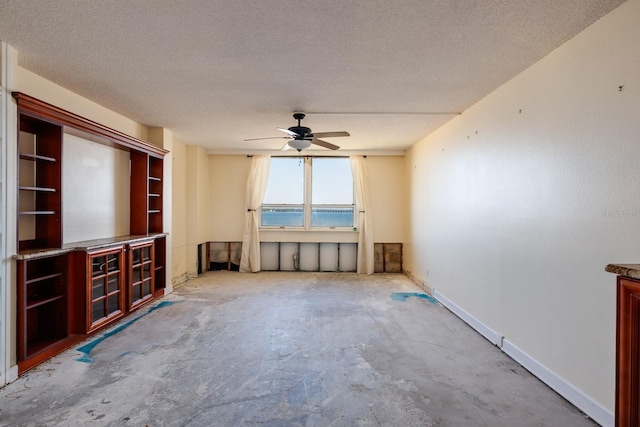 unfurnished living room featuring a textured ceiling, unfinished concrete flooring, a ceiling fan, and baseboards