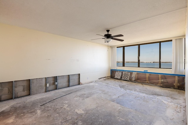 spare room featuring a water view, ceiling fan, and unfinished concrete floors