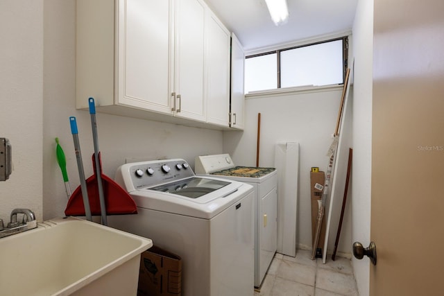 washroom with cabinet space, washing machine and dryer, light tile patterned floors, and a sink