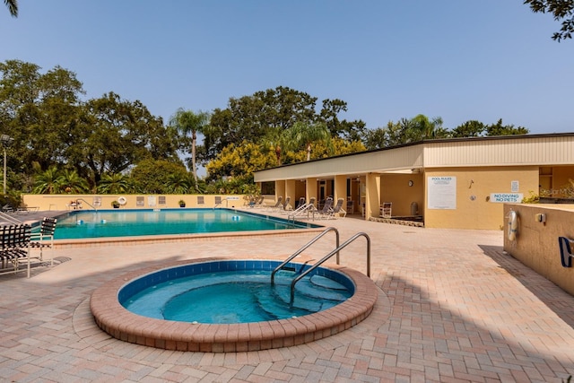 pool with a hot tub, fence, and a patio