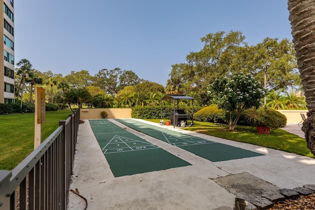 view of property's community with shuffleboard, a lawn, and fence