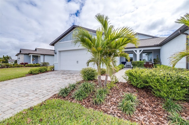 view of front of property featuring decorative driveway, an attached garage, and stucco siding