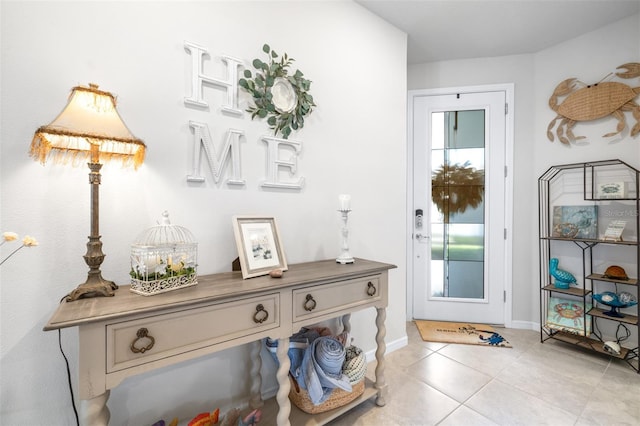 doorway to outside with a healthy amount of sunlight, light tile patterned floors, and baseboards