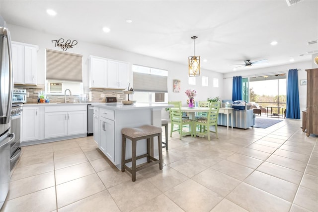 kitchen featuring light tile patterned floors, decorative backsplash, a center island, light countertops, and white cabinetry