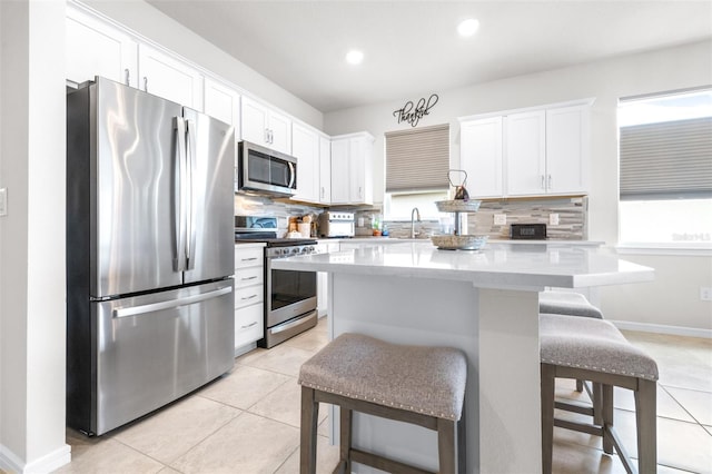 kitchen with a breakfast bar, light tile patterned floors, stainless steel appliances, and decorative backsplash