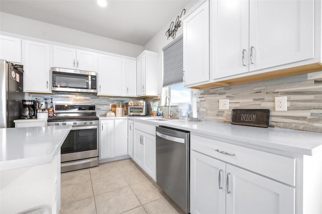 kitchen featuring light tile patterned floors, white cabinets, appliances with stainless steel finishes, light countertops, and a sink