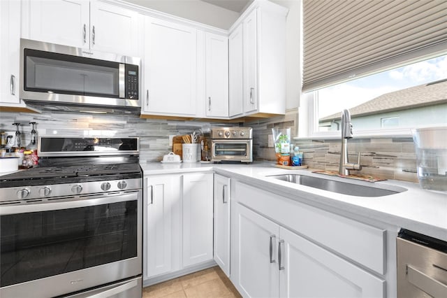 kitchen with decorative backsplash, appliances with stainless steel finishes, light countertops, and a sink