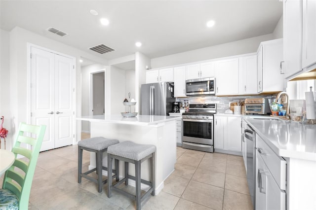 kitchen featuring appliances with stainless steel finishes, a center island, visible vents, and a sink