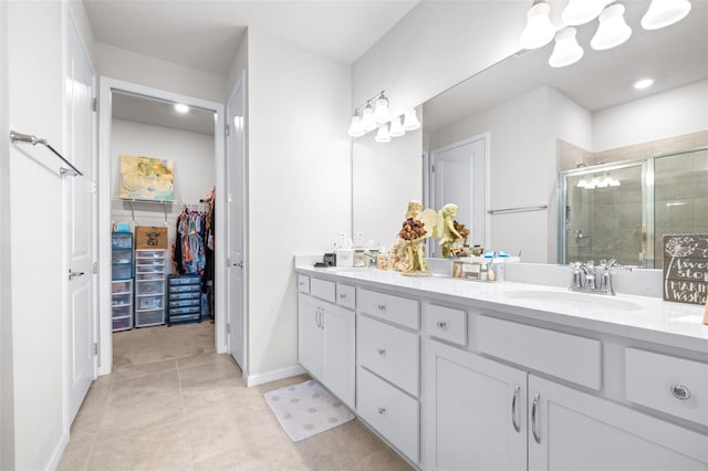 bathroom with double vanity, a shower stall, a walk in closet, and a sink