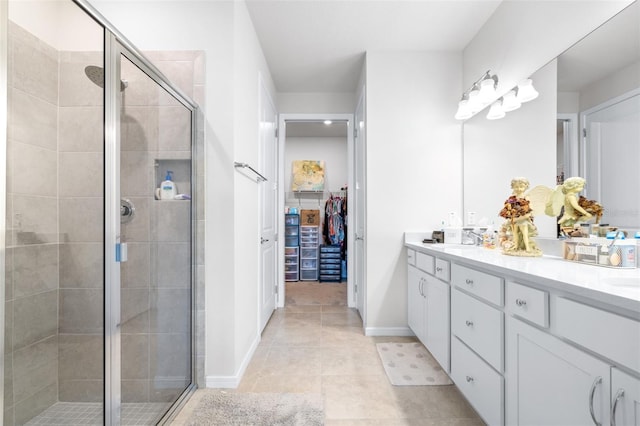 bathroom with double vanity, a spacious closet, a sink, a shower stall, and tile patterned floors