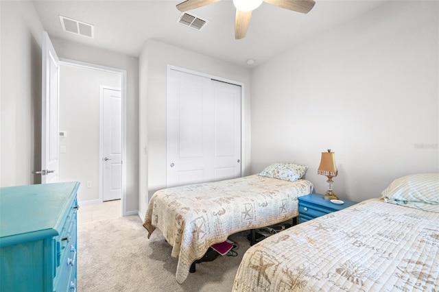 bedroom with ceiling fan, visible vents, a closet, and light colored carpet