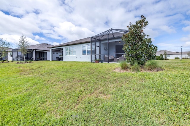 back of property with glass enclosure, a lawn, and stucco siding