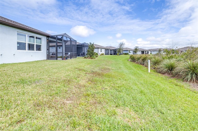 view of yard with glass enclosure and a residential view