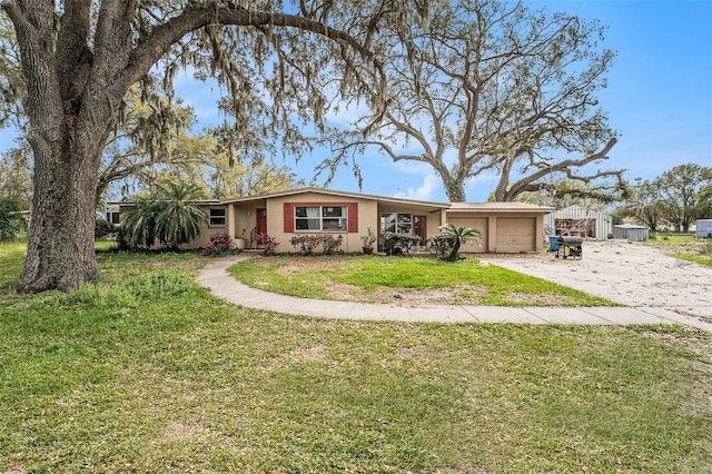 single story home with a garage, driveway, a front lawn, and stucco siding