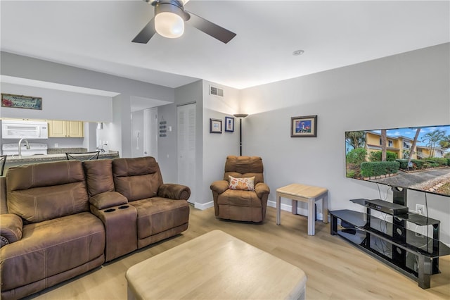 living area featuring light wood-style flooring, visible vents, and baseboards