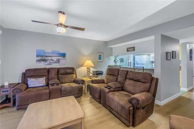 living room with ceiling fan, light wood-style flooring, and baseboards