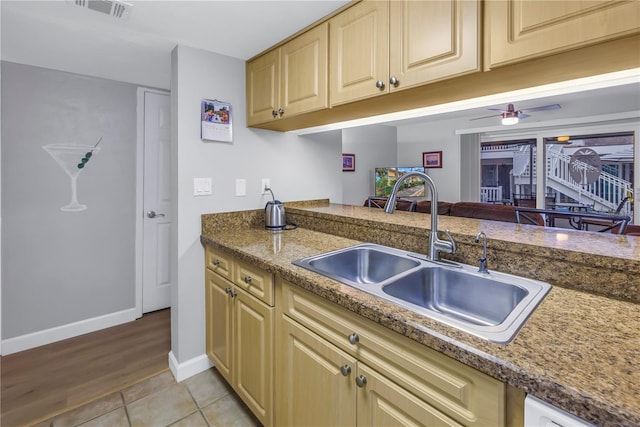 kitchen featuring light tile patterned floors, baseboards, visible vents, white dishwasher, and a sink