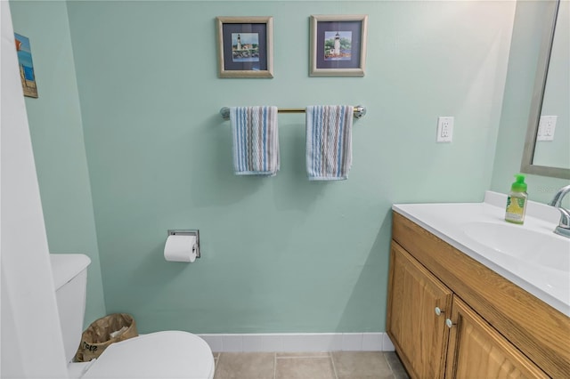 bathroom with tile patterned flooring, baseboards, vanity, and toilet