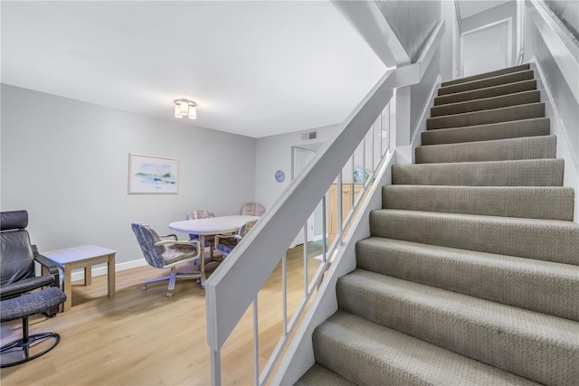 stairs featuring visible vents, baseboards, and wood finished floors