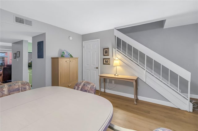 dining area with electric panel, baseboards, visible vents, stairway, and wood finished floors