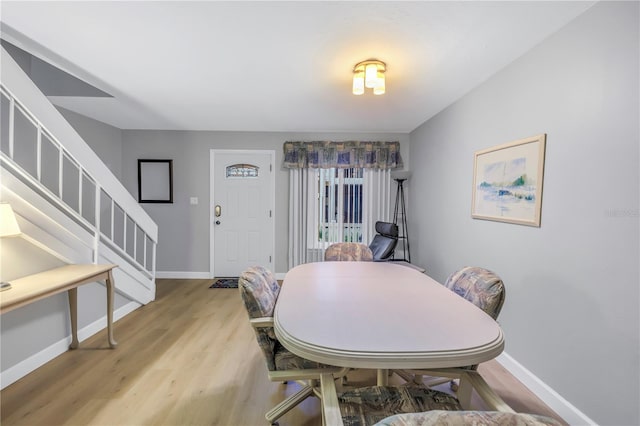 dining room featuring baseboards, stairway, and light wood-style floors