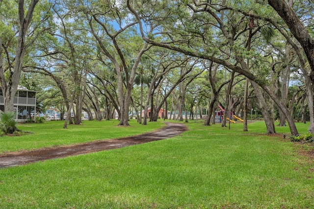 view of property's community featuring playground community and a yard