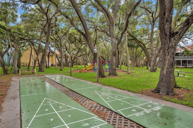 view of home's community featuring shuffleboard, playground community, and a yard