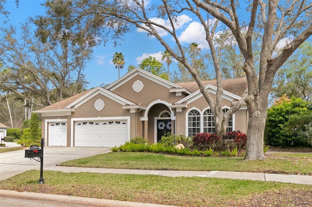 view of front of property with a front lawn, driveway, an attached garage, and stucco siding