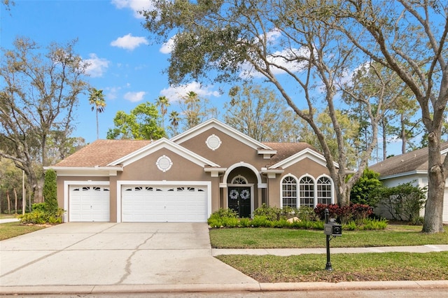 view of front of house with driveway, a front lawn, an attached garage, and stucco siding