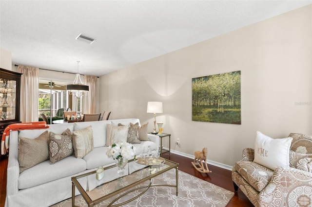 living room featuring visible vents, baseboards, and wood finished floors