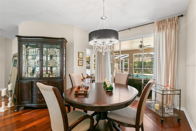 dining room with baseboards, dark wood finished floors, and ceiling fan with notable chandelier