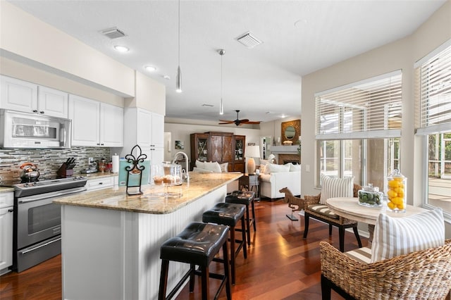 kitchen featuring visible vents, white microwave, light stone counters, dark wood-style flooring, and stainless steel electric range