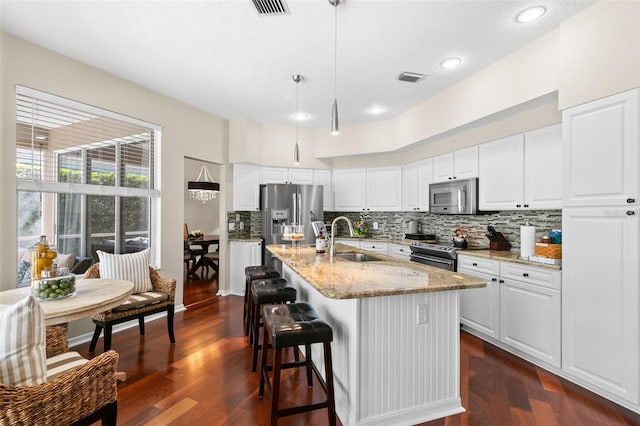 kitchen featuring a sink, visible vents, appliances with stainless steel finishes, light stone countertops, and tasteful backsplash