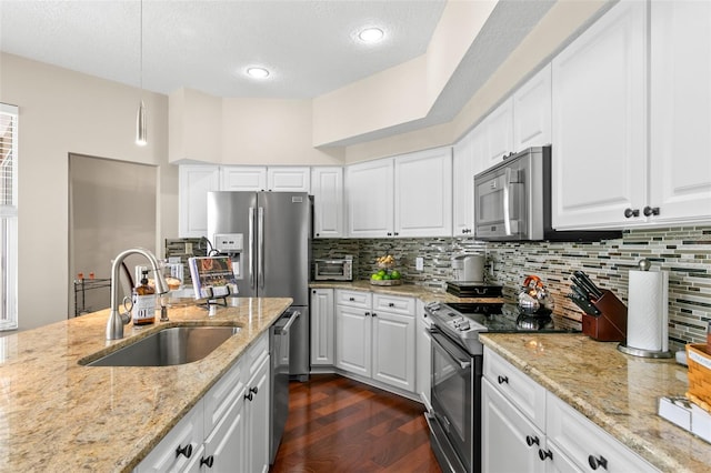 kitchen with a sink, appliances with stainless steel finishes, decorative backsplash, light stone countertops, and dark wood finished floors