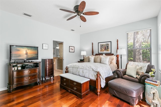 bedroom featuring dark wood-style floors, ceiling fan, visible vents, and ensuite bathroom