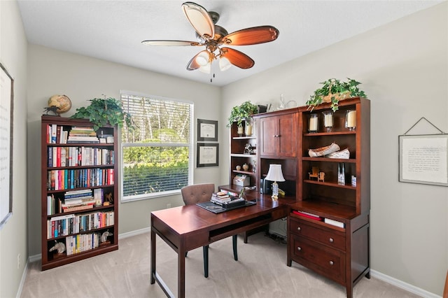 office space with baseboards, a ceiling fan, and light colored carpet