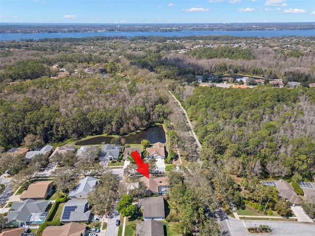 drone / aerial view featuring a water view, a residential view, and a wooded view