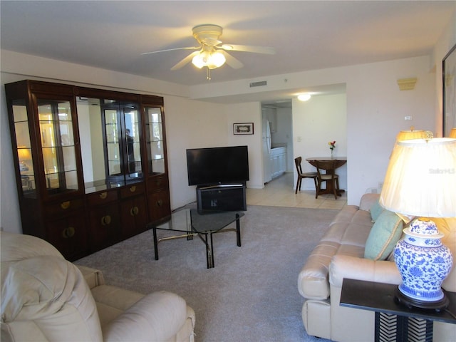 carpeted living room with ceiling fan, visible vents, and tile patterned floors