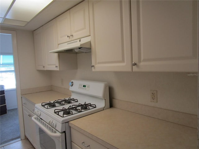 kitchen with light countertops, white gas range oven, white cabinetry, and under cabinet range hood