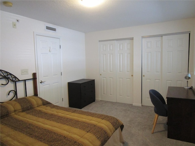 bedroom with carpet flooring, visible vents, and multiple closets