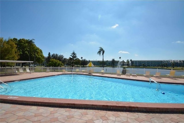 community pool with a patio area and fence