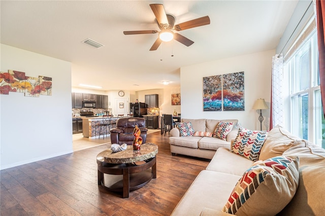 living area featuring baseboards, ceiling fan, visible vents, and wood finished floors