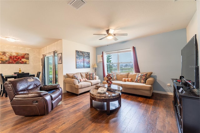 living area featuring baseboards, visible vents, ceiling fan, and dark wood-type flooring