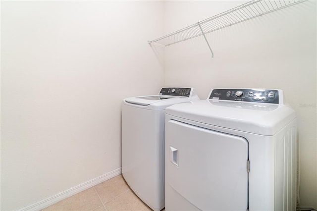 washroom featuring laundry area, baseboards, washer and dryer, and light tile patterned flooring