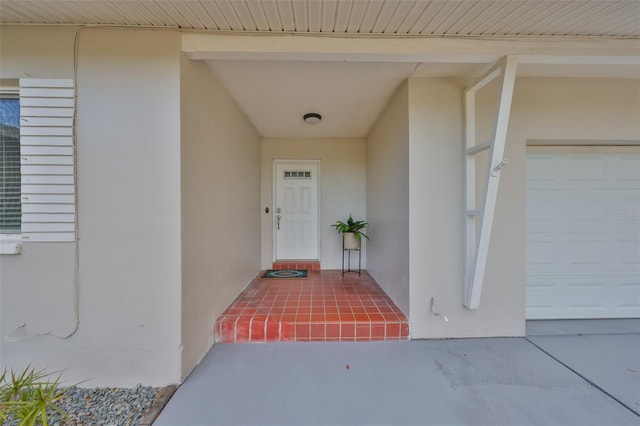 view of exterior entry featuring a garage and stucco siding