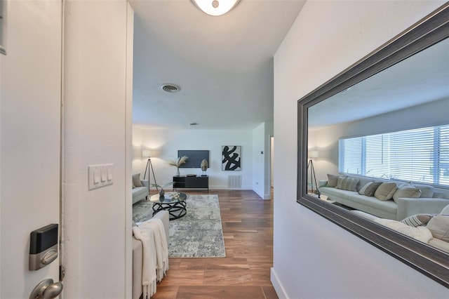 hall featuring wood finished floors, visible vents, and baseboards