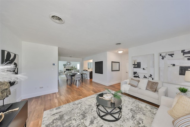 living area with visible vents, baseboards, and wood finished floors