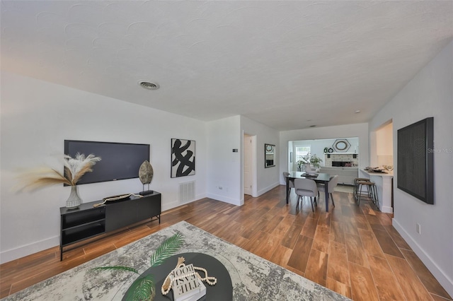 living room with baseboards, visible vents, and wood finished floors