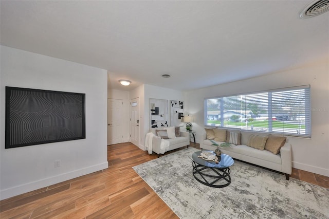 living area with wood finished floors, visible vents, and baseboards